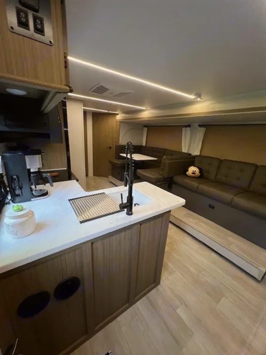 Modern RV rental interior featuring a full kitchen, comfortable dinette, and spacious living area. Ready for your adventure!. Forest River 273QBXL 2025