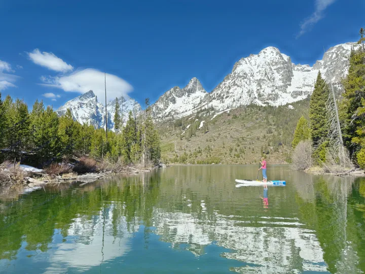 Paddleboarder on a clear mountain lake, snowy peaks reflecting. Ideal RV rental destination!. Ford Ranger 2300 Cc 2022