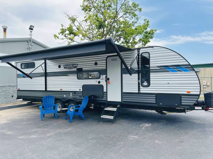 A sleek Salem Cruise Lite travel trailer rv rental, complete with an extended awning and blue chairs for outdoor leisure.. Forest River Salem Cruise Lite 2022