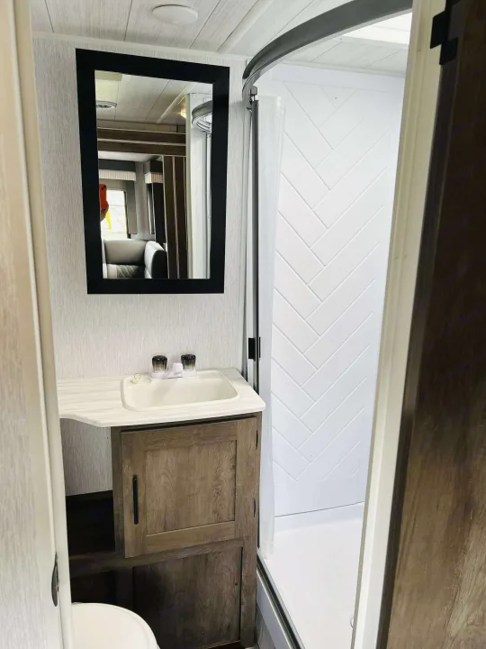 RV rental: Bright RV bathroom featuring a vanity with a sink, mirror, and white herringbone shower walls.. Forest River Salem Cruise Lite 2022