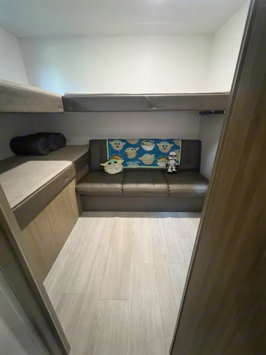 RV rental: A cozy bunkhouse interior with stacked beds, a sofa featuring Grogu & Stormtrooper decor, and wood-look floor.. Forest River 273QBXL 2025