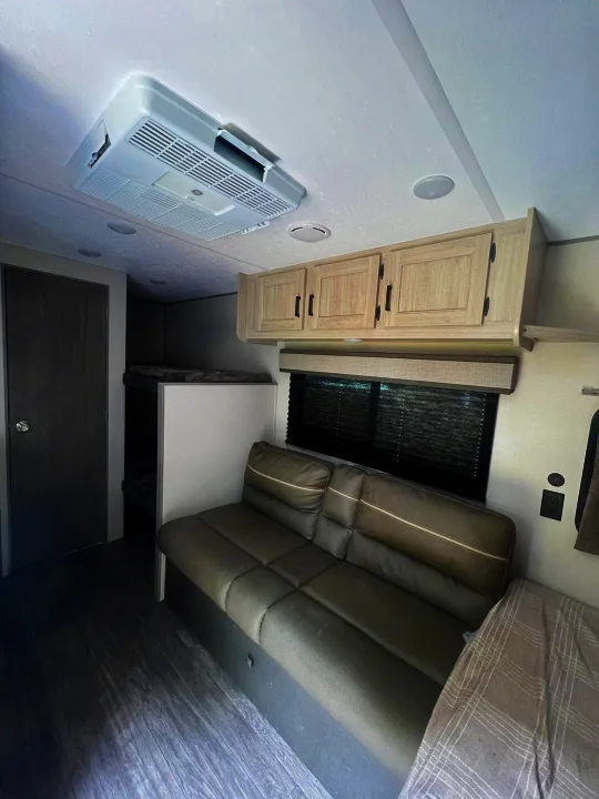 Cozy rv rental interior with sofa, bunk beds, overhead cabinets, and ceiling AC unit for your trip.. Forest River Aurora Aurora 2025