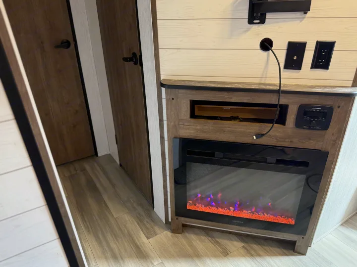 RV rental interior: modern electric fireplace with faux flames, media center, power outlets, and wood-look doors.. 5SFPB372XME475890 Pioneer 2021