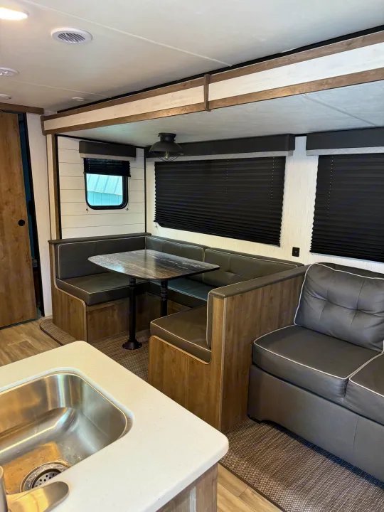 Inside a comfortable RV rental, showing a U-shaped dinette, sofa, and kitchen sink in the foreground.. 5SFPB372XME475890 Pioneer 2021