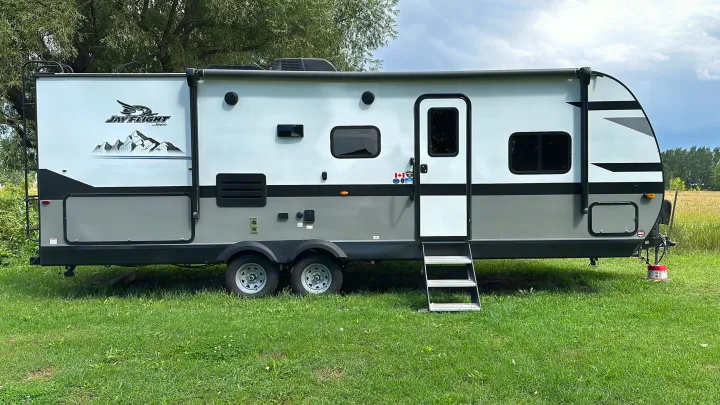 Spacious Jay Flight travel trailer, perfect for your next RV rental adventure, parked on green grass with trees.. JAYFLIGHT 242BHSW-G 2023