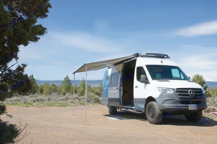 White and teal camper van RV rental with awning extended, parked on a dirt track amidst trees for outdoor adventures.. Mercedes-Benz Sprinter 2020