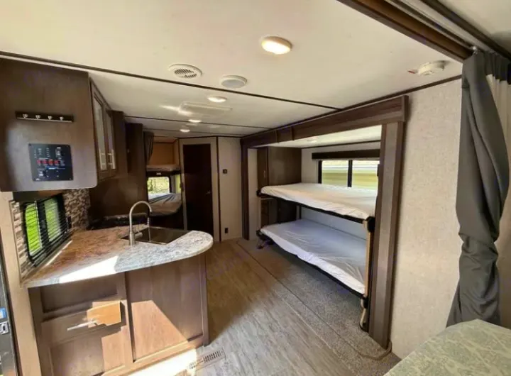 Spacious RV rental interior featuring a modern kitchen with sink and multiple bunk beds, perfect for family adventures.. Dutchmen 2340BHS 2020