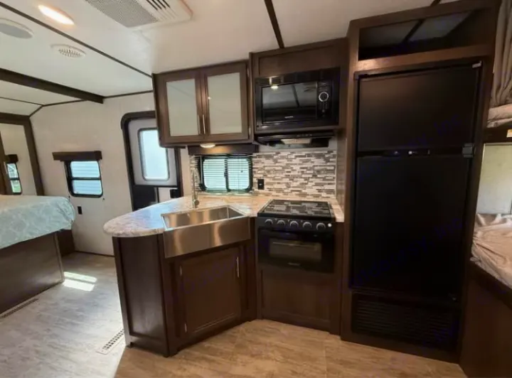 Spacious RV rental interior featuring a full kitchen with sink, stove, microwave, fridge, and a comfy bedroom area. Ideal for travel.. Dutchmen 2340BHS 2020