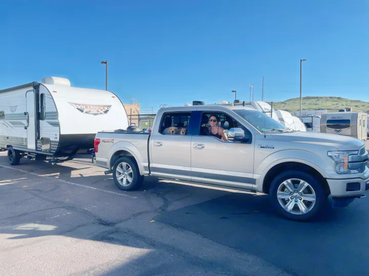 Happy woman & two dogs in a pickup truck towing a Wildwood FSX travel trailer, set for an RV rental camping trip.. Forest River Wildwood FSX 2022