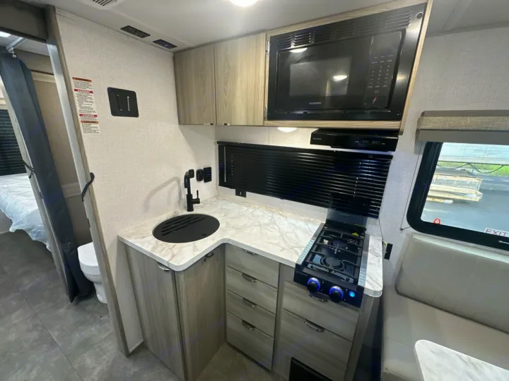 Inside this RV rental: compact kitchen with sink, stove & microwave, plus dinette, bedroom, and bath.. Forest River Wildwood FSX 2022