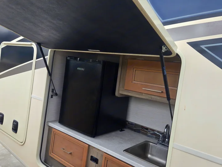 RV rental outdoor kitchen: a black mini-fridge, sink, and counter space, perfect for convenient camping trips.. Coachmen Mirada 2020