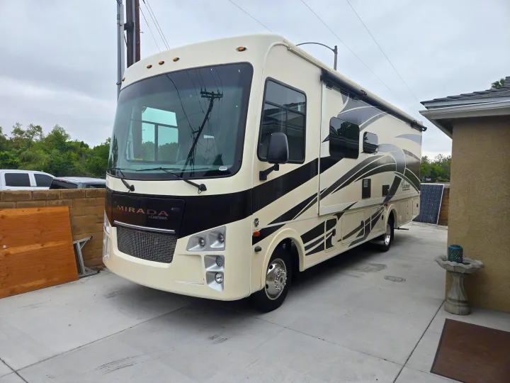 Large, cream-colored Coachmen Mirada RV parked on a driveway, ready for adventure. Perfect for your next RV rental trip.. Coachmen Mirada 2020