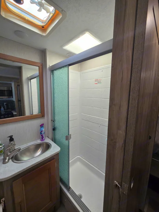 Compact RV rental bathroom featuring a sink, mirror, and shower with sliding door, maximizing space for travelers.. Coachmen Mirada 2020