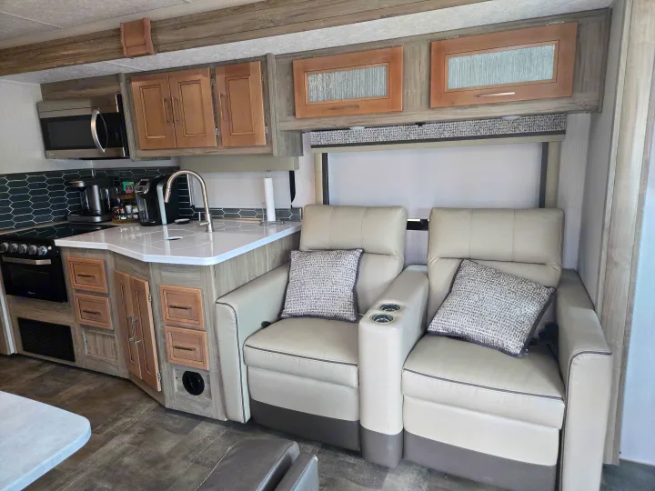 Modern RV rental interior with a well-equipped kitchen and comfortable theater seating recliners, perfect for relaxing.. Coachmen Mirada 2020
