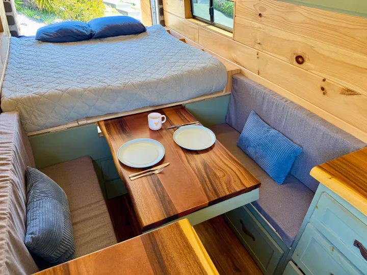 Cozy RV rental interior featuring a raised bed, dining table set for two, and comfortable bench seating.. Dodge Sprinter 3500 2007