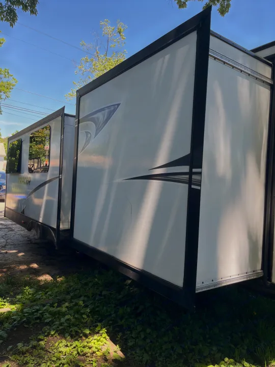 White Tracer travel trailer RV rental with extended slide-out, parked on dirt, sunny.. Forest River Tracer Breeze 2019