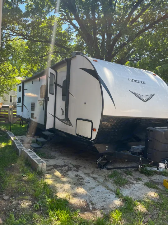 A white Tracer Breeze RV rental is parked outdoors under a bright sky and large trees, ready for adventure.. Forest River Tracer Breeze 2019