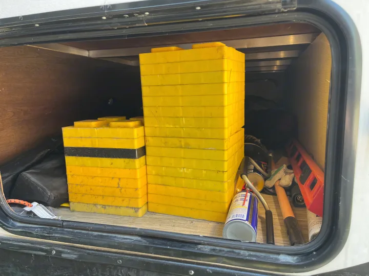 RV rental storage bay showing yellow leveling blocks and camping tools.. Forest River Tracer Breeze 2019