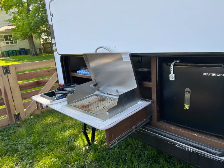 Outdoor kitchen of an RV rental: pull-out grill, sink, and RVISION fridge for easy outdoor cooking while camping.. Forest River Tracer Breeze 2019