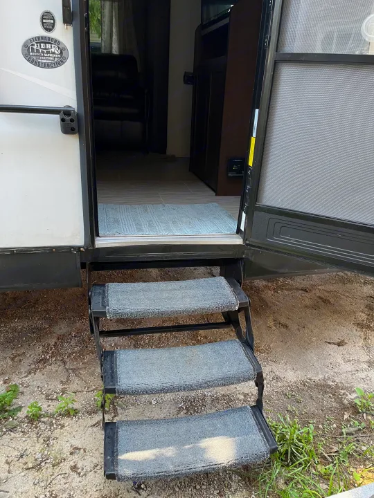 RV rental entrance: open door, three carpeted steps, and view of the interior with a light blue rug.. Forest River Tracer Breeze 2019