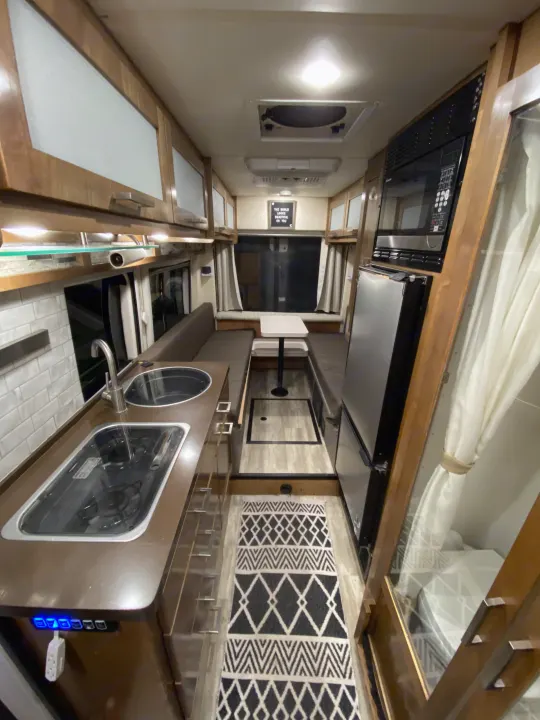Step inside this RV rental showcasing a modern kitchen with stove, sink, microwave, fridge, and cozy dinette.. Forest River Coachmen Crossfit 2018
