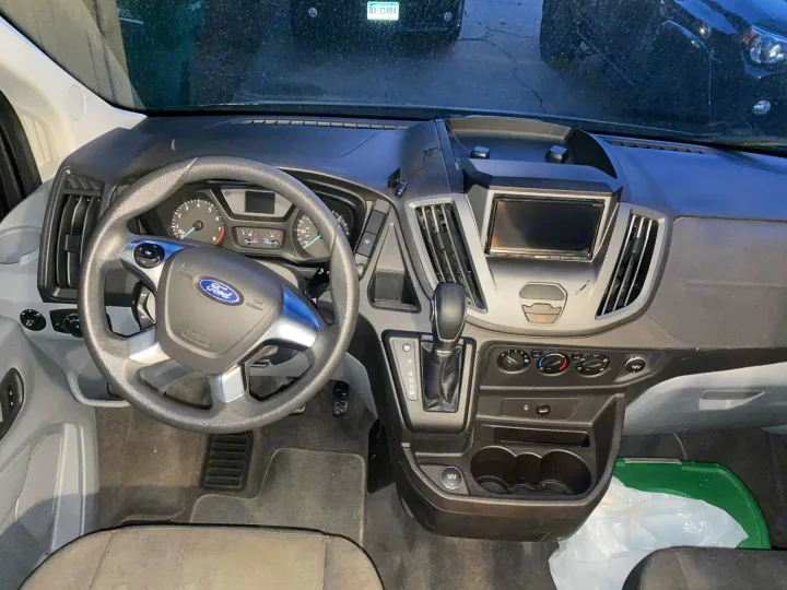 Driver's view of an RV rental van's interior, showing a Ford steering wheel, dashboard, automatic shifter, and climate controls.. Forest River Coachmen Crossfit 2018