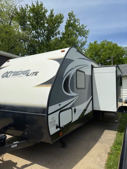 White & gray Extreme Lite Forest River travel trailer, with slide-out extended, parked on a driveway. Great rv rental option!. Forest River Vibe Extreme Lite 2017
