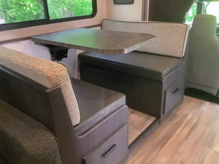 RV rental dinette with cozy benches and a wall-mounted table for dining and relaxation.. Forest River Solera 27 DSE 2023