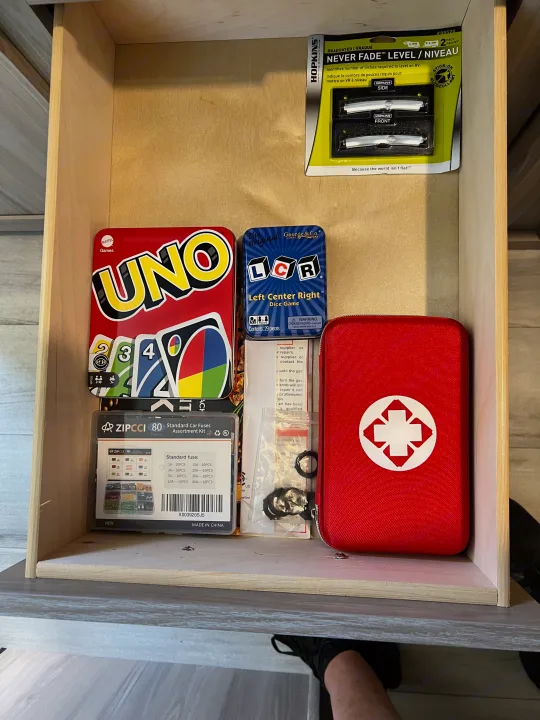 An RV rental drawer packed with essentials: UNO, LCR games, car fuses, a first aid kit, and RV leveling tools for any adventure.. Coleman Lantern 17B 2025