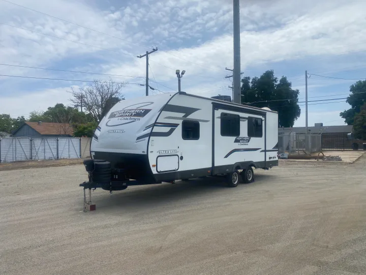 A white Northern Spirit by Coachmen travel trailer sits on a gravel lot, ready for your next rv rental adventure.. Coachmen Northern  Spirit Ultra Lite 2024