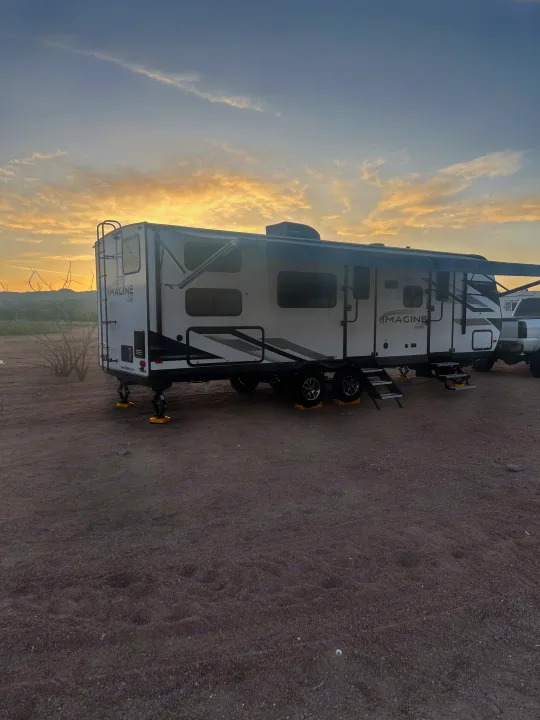 An Imagine XLS RV rental is parked in a serene desert landscape at sunset, ready for adventure.. Grand Designs 25DBE 2025