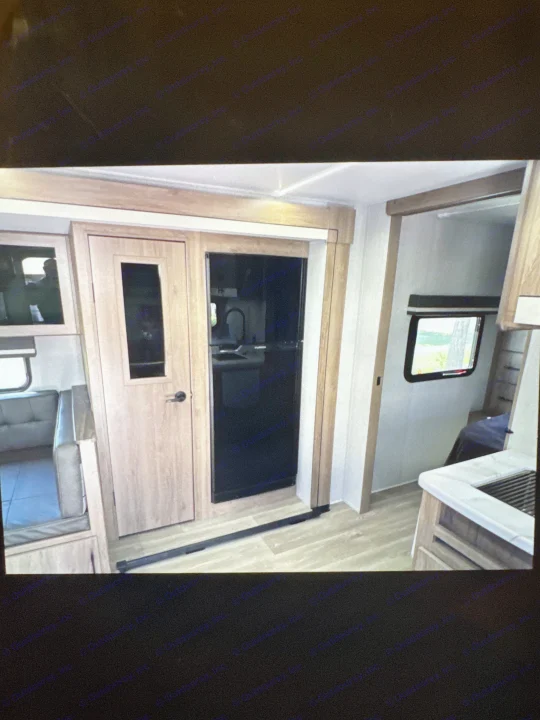 RV rental: interior with dinette, modern wood-look cabinetry, black fridge, and a glimpse of the bedroom.. Grand Designs 25DBE 2025