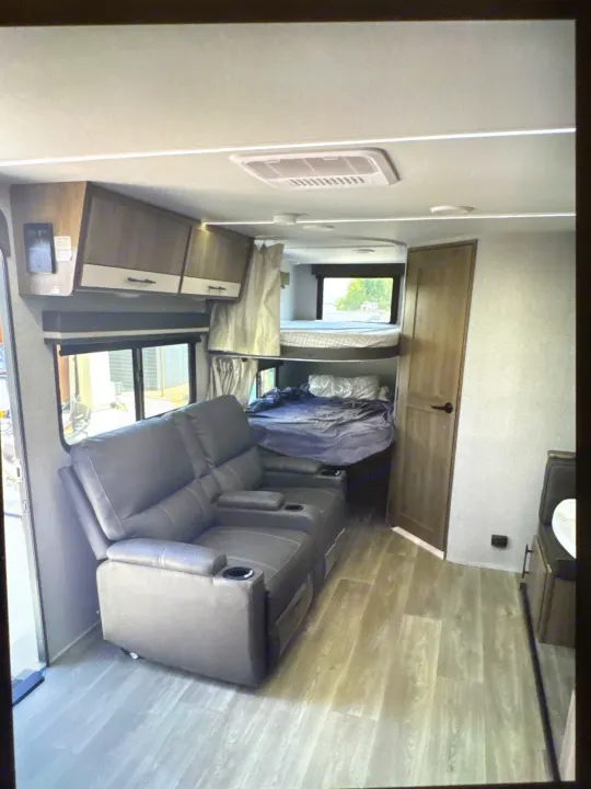 RV rental interior: cozy recliners, bunk beds, overhead cabinets, and wood floors for a comfortable trip.. Grand Designs 25DBE 2025