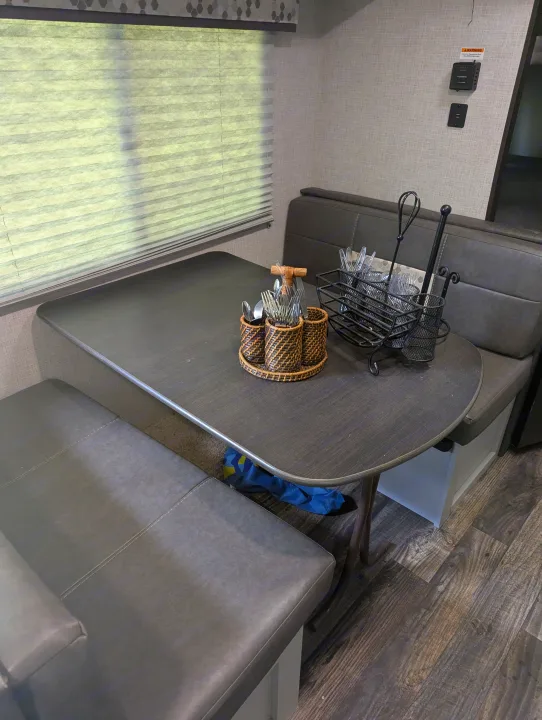 RV rental interior: Dining dinette with dark table, gray bench seating, and practical cutlery organization.. Keystone RV Bullet Crossfire 2020