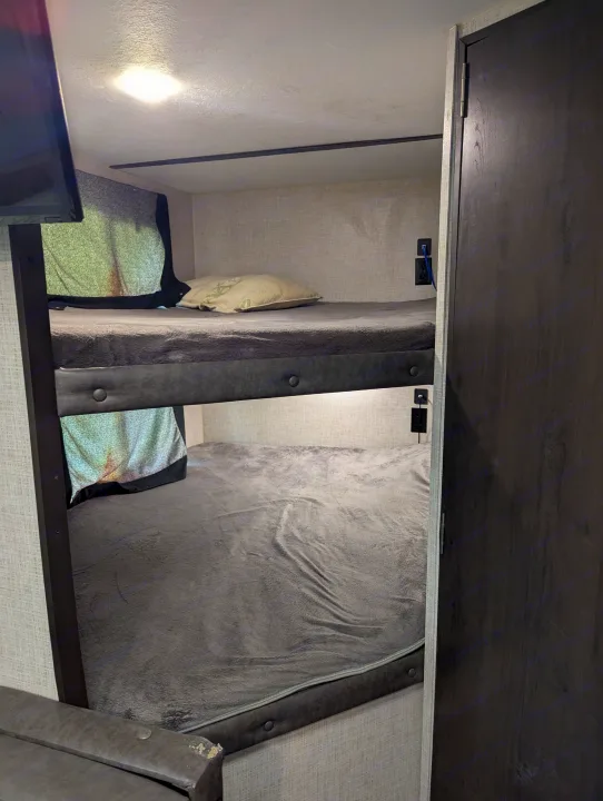 Cozy RV rental bunk beds, perfect for family sleeping in a compact space. Features outlets and a door.. Keystone RV Bullet Crossfire 2020