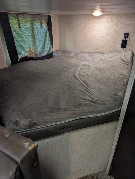 RV rental interior: a plush gray bunk bed with window shade and power outlet.. Keystone RV Bullet Crossfire 2020
