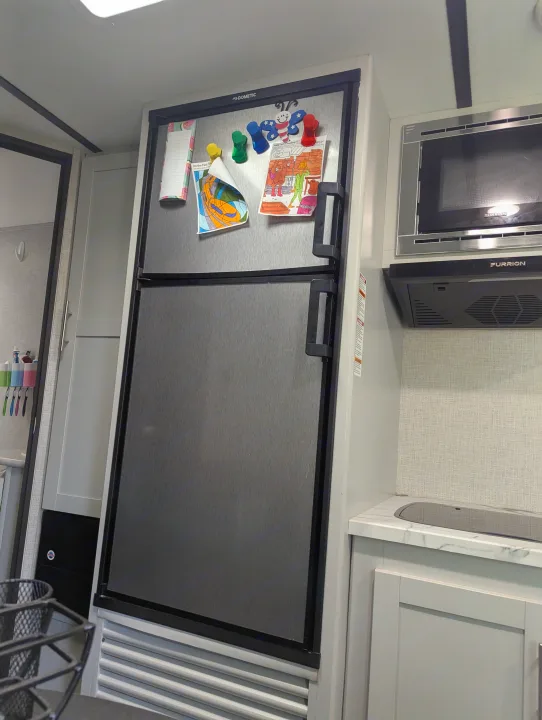 Modern RV rental kitchen featuring a Dometic refrigerator, Furrion microwave, and sink area with personal touches.. Keystone RV Bullet Crossfire 2020