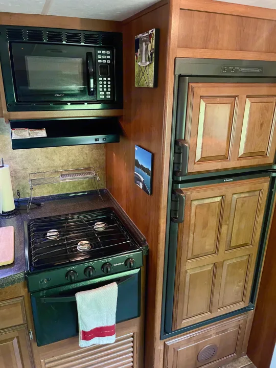 Compact RV rental kitchen with microwave, stove, oven, and Dometic fridge, perfect for your adventures.. Coachmen Freedom Express 2013