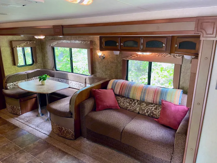 Cozy RV rental interior featuring a comfortable dinette and sofa, perfect for relaxing after a day of adventure.. Coachmen Freedom Express 2013