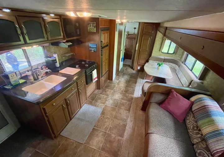 RV rental interior: kitchen with stove, sink, and fridge; U-shaped dinette, and comfortable sofa area.. Coachmen Freedom Express 2013