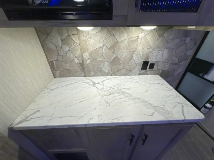 This RV rental features a bright kitchen with a marble-look countertop, stone backsplash, and under-cabinet lighting.. Forest River Cherokee Alpha Wolf 2020
