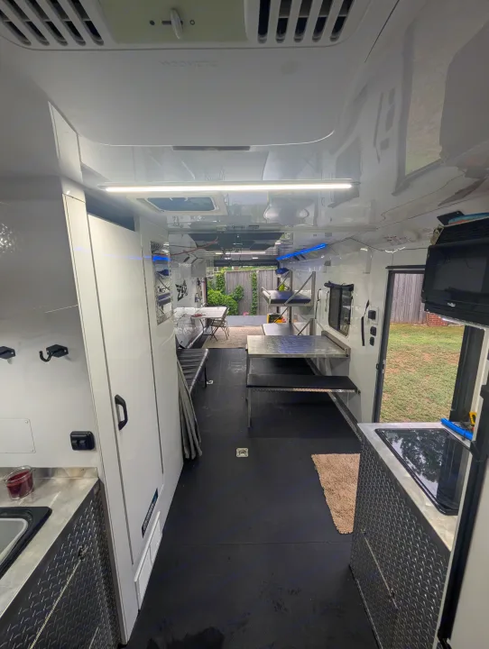 Inside a modern RV rental: durable black floors, diamond plate kitchen, Dometic AC, and flexible seating for travel.. Trails West RPM Toy Hauler 2023