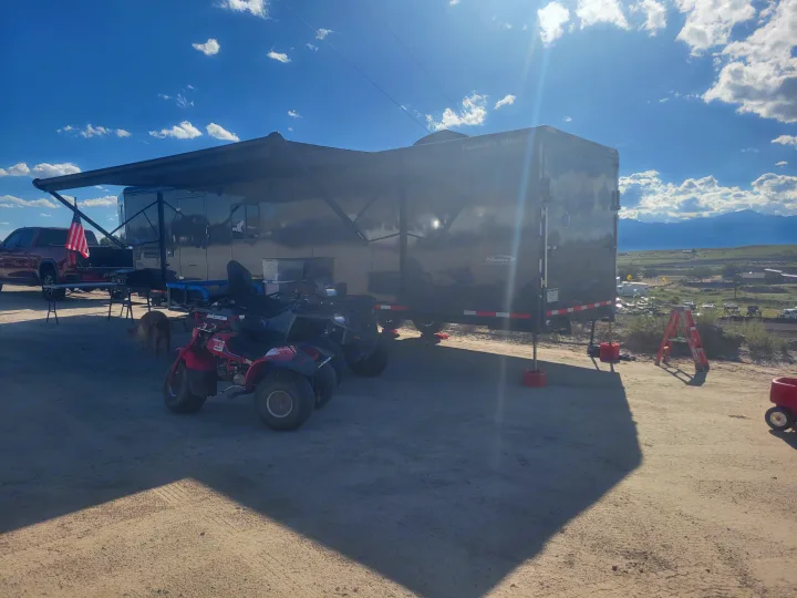 Enjoying the outdoors! This RV rental setup features a toy hauler, ATVs, and a dog.. Trails West RPM Toy Hauler 2023