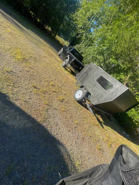 Black pickup truck with a small, rugged travel trailer on a gravel lot, perfect for your next outdoor rv rental trip.. Custom Squaredrop Trailer 2021