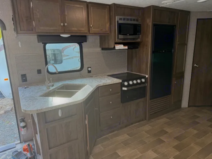 RV rental kitchen: modern appliances, sink, counter, and cabinetry in a travel trailer interior.. Dutchmen Coleman Lantern 2020