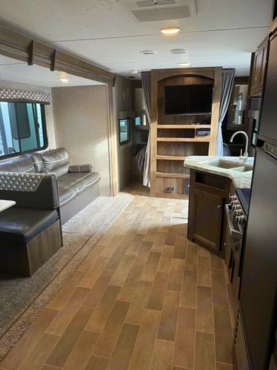 RV rental interior: living area with dinette/sofa, kitchen, entertainment center, and bunk beds. Explore comfort on the go.. Dutchmen Coleman Lantern 2020