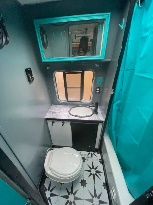 Experience comfort in this RV rental! A well-designed bathroom with toilet, sink, mirror, shower, and stylish teal accents.. Skyline Century 1985
