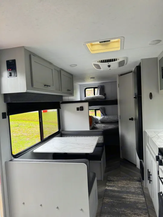 Inside a modern **RV rental**: a bright dinette, bunk beds, and compact kitchen offer comfort. Perfect for travel.. Forest River Salem FSX PLATINUM 2021