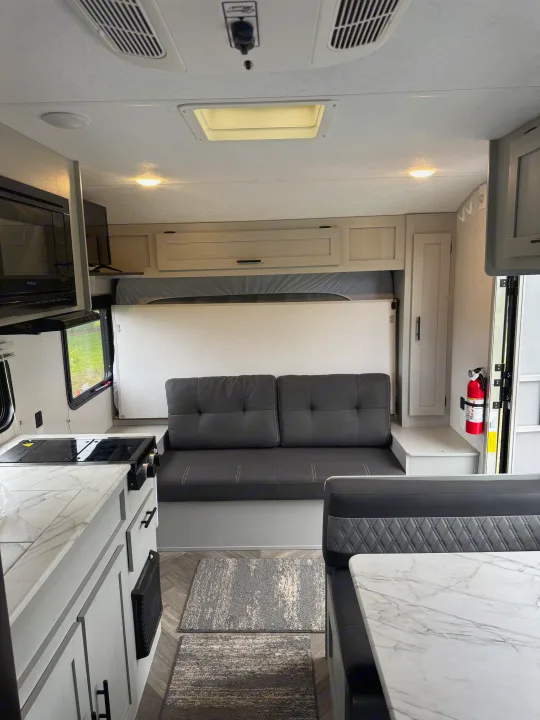 View inside a modern RV rental, featuring a compact kitchen, versatile sofa bed, and dining dinette. A cozy, functional living space.. Forest River Salem FSX PLATINUM 2021