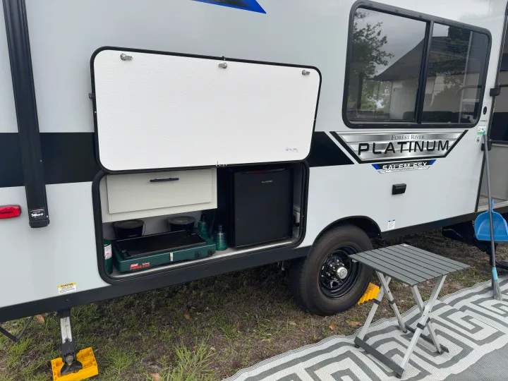 This RV rental features an open outdoor kitchen with a Coleman stove, mini-fridge, and a neat campsite setup, including a table.. Forest River Salem FSX PLATINUM 2021